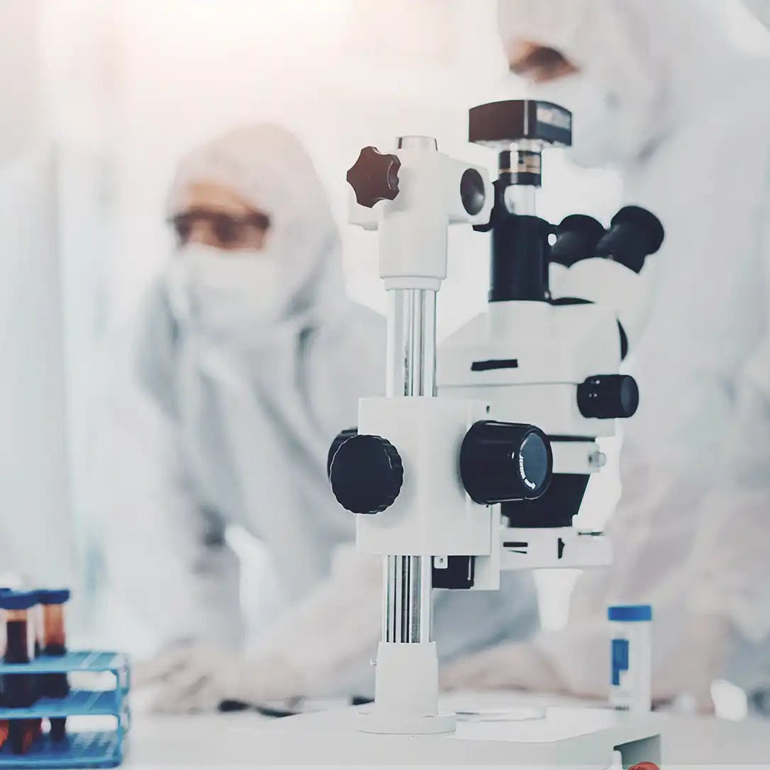 image of microscope with scientists in the background